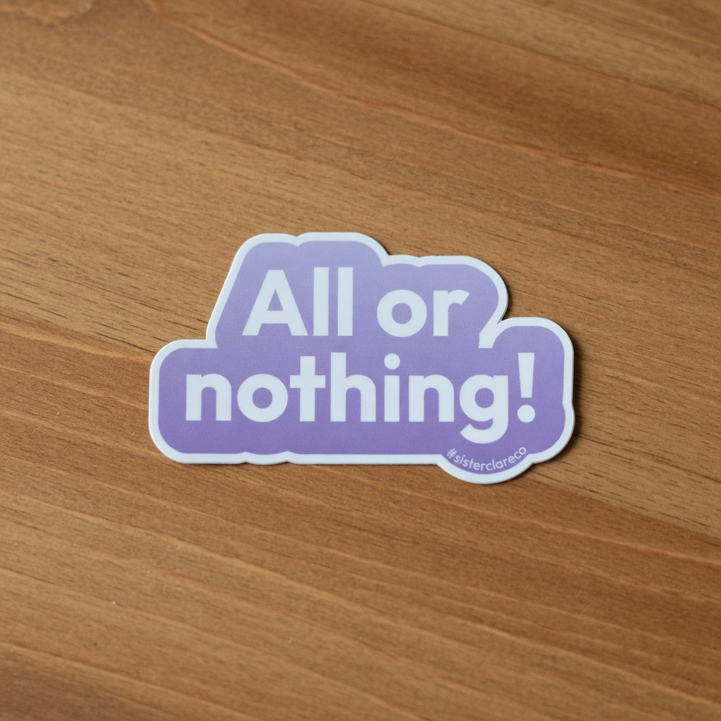 Exact 2-inch 'ALL or nothing!' Sister Clare Crockett die-cut sticker shown at true-to-life 2-inch physical scale on warm wood surface, perfect proportions and colors preserved, no alterations.