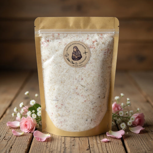 Professional square hero product photograph of Athleta Christi Mineral Soak pouch centered on warm rustic wood with soft studio lighting and subtle pink rose accents, evoking warrior strength and inviting customers into a restorative bath ritual.