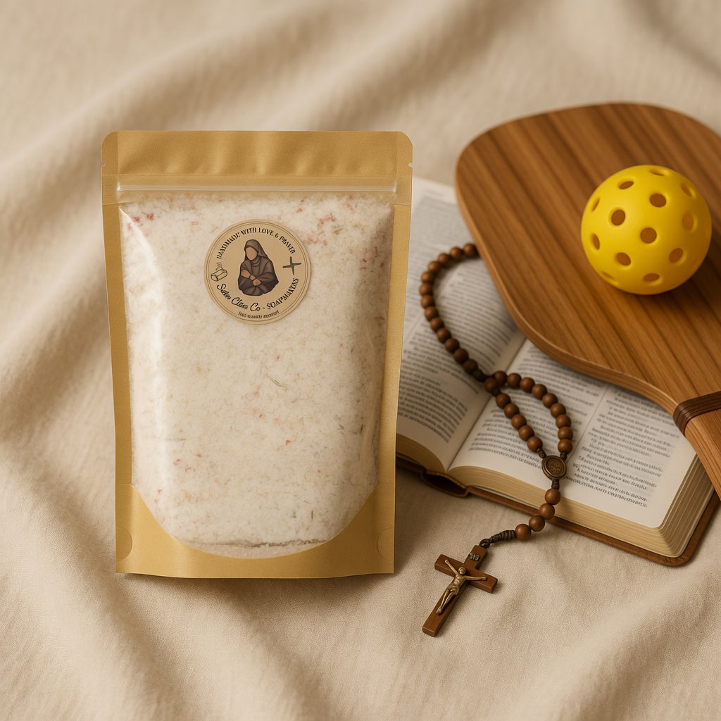 Warm square lifestyle photograph of Athleta Christi Mineral Soak pouch beside an open Bible, rosary, and a pickleball paddle with ball on soft linen, conveying spiritual strength, faith-filled recovery after hard training, and the joy of pressing on as a warrior for Christ.