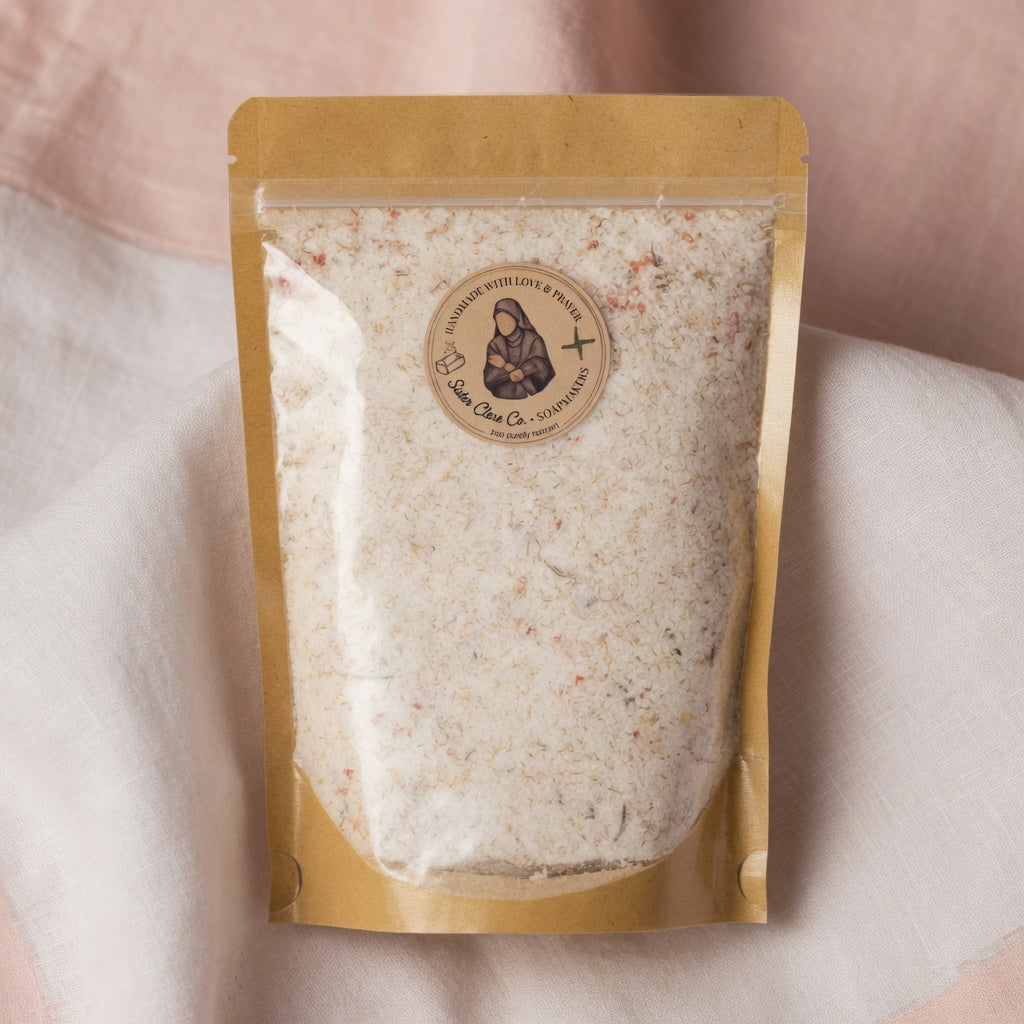 Detailed square close-up product photograph of Athleta Christi Mineral Soak pouch showing luxurious texture of white salts, pink accents, and botanicals through the transparent window, placed on soft linen with perfect lighting.