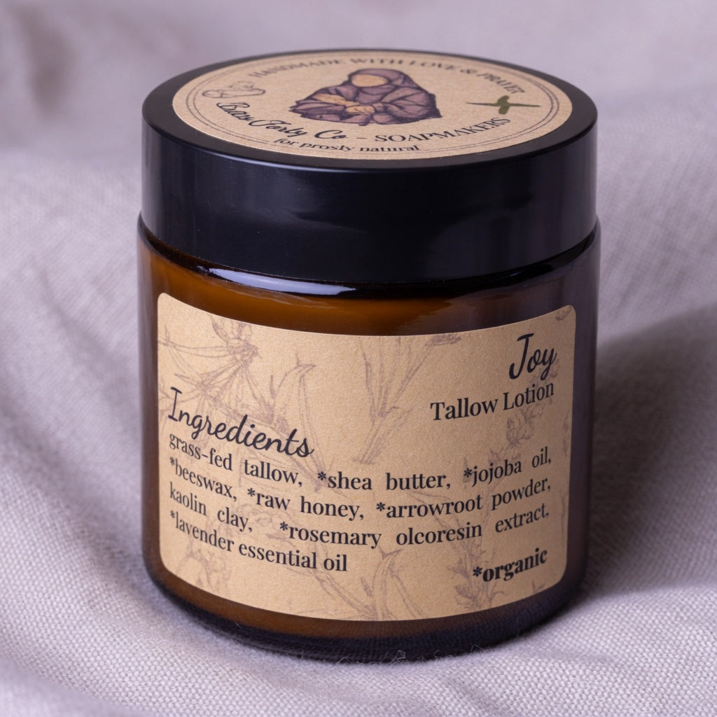 Close-up of Joy Tallow Lotion jar on soft linen fabric highlighting the luxurious creamy texture and elegant labeling