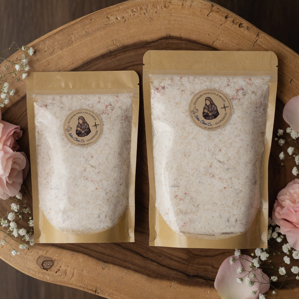 Square product photograph of small and large Athleta Christi Mineral Soak pouches arranged side by side on natural wood or stone surface with soft shadows, floral accents, and elegant styling that helps customers visualize stocking up for their faith-filled recovery routine.