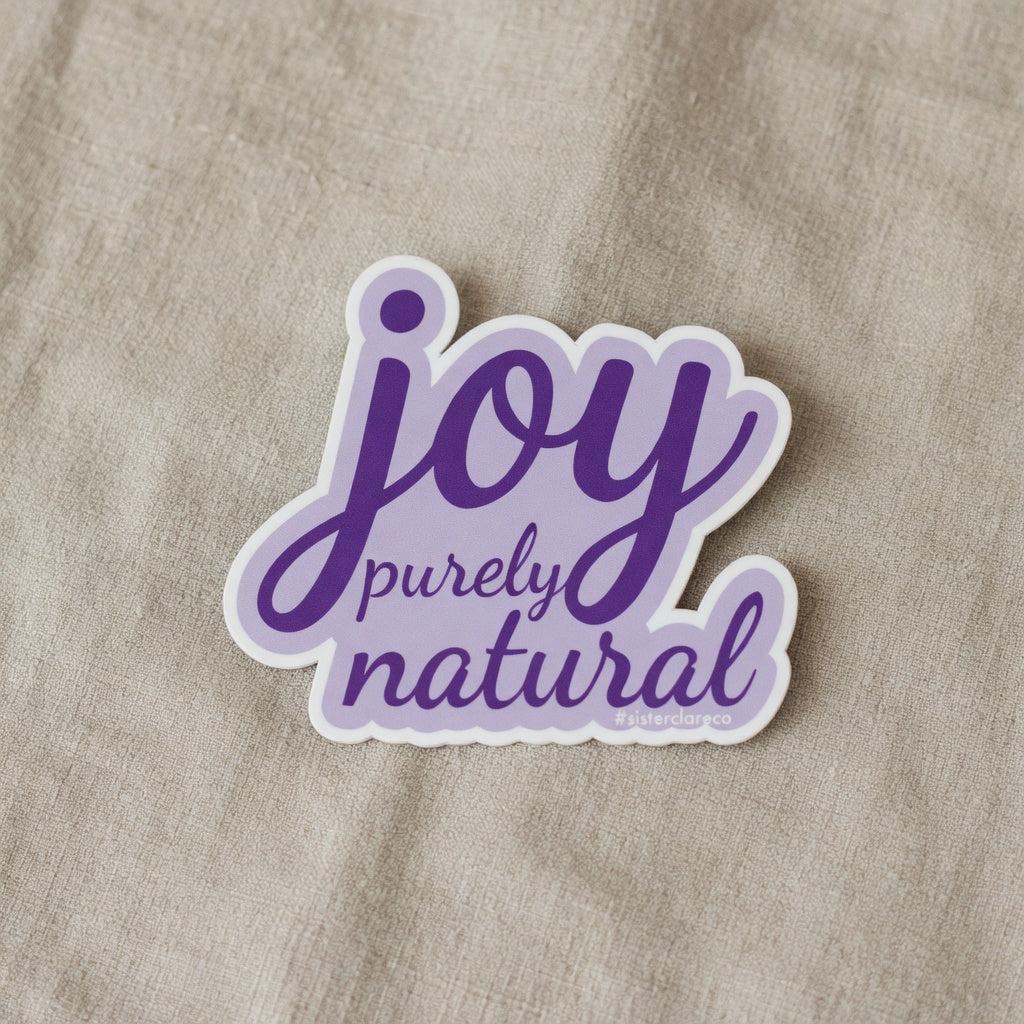 Exact 2-inch 'joy purely natural' Sister Clare Crockett die-cut sticker on soft linen at true-to-life 2-inch physical scale, crisp edges and perfect proportions, zero alterations.