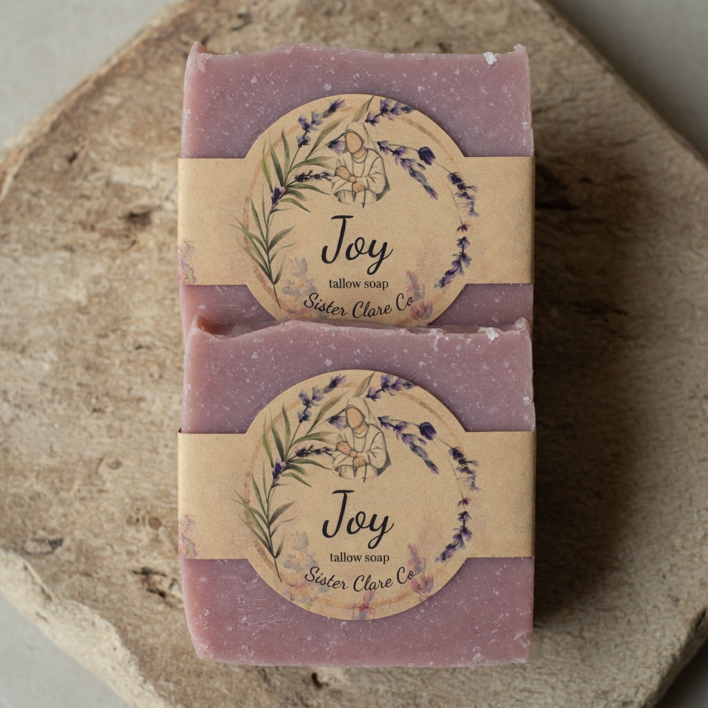 Two bars of lavender soap with 'Joy' labels on a wooden surface