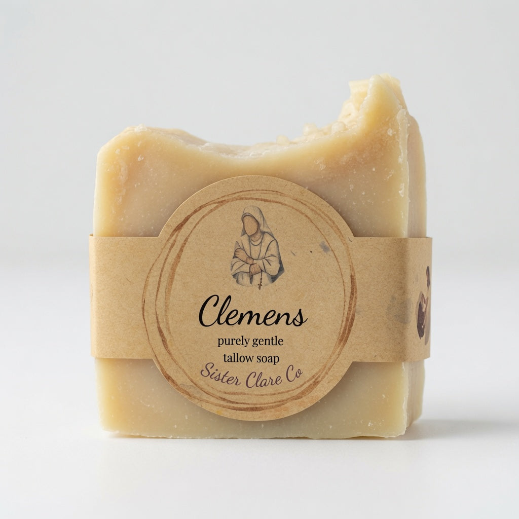 A single bar of pale beige tallow soap wrapped in a kraft paper band with a round label reading 'Clemens' and 'Sister Clare Co', photographed on a clean white background.