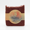 A rectangular bar of Sister Clare Co. Faustina tallow soap, wrapped in a beige paper band with a circular label featuring a watercolor illustration of a robed figure.