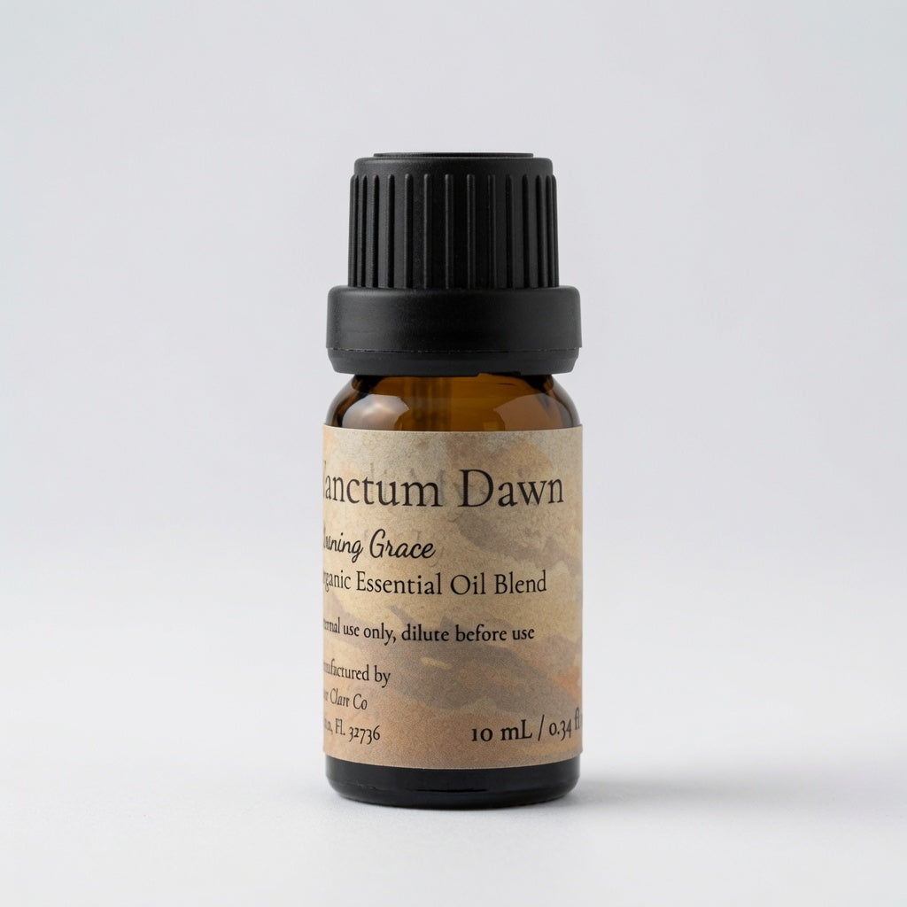 A 10 mL amber glass bottle of essential oil blend with a black ribbed cap and a beige label reading 'Sanctum Dawn' and 'Morning Grace Organic Essential Oil Blend' on a light gray background.