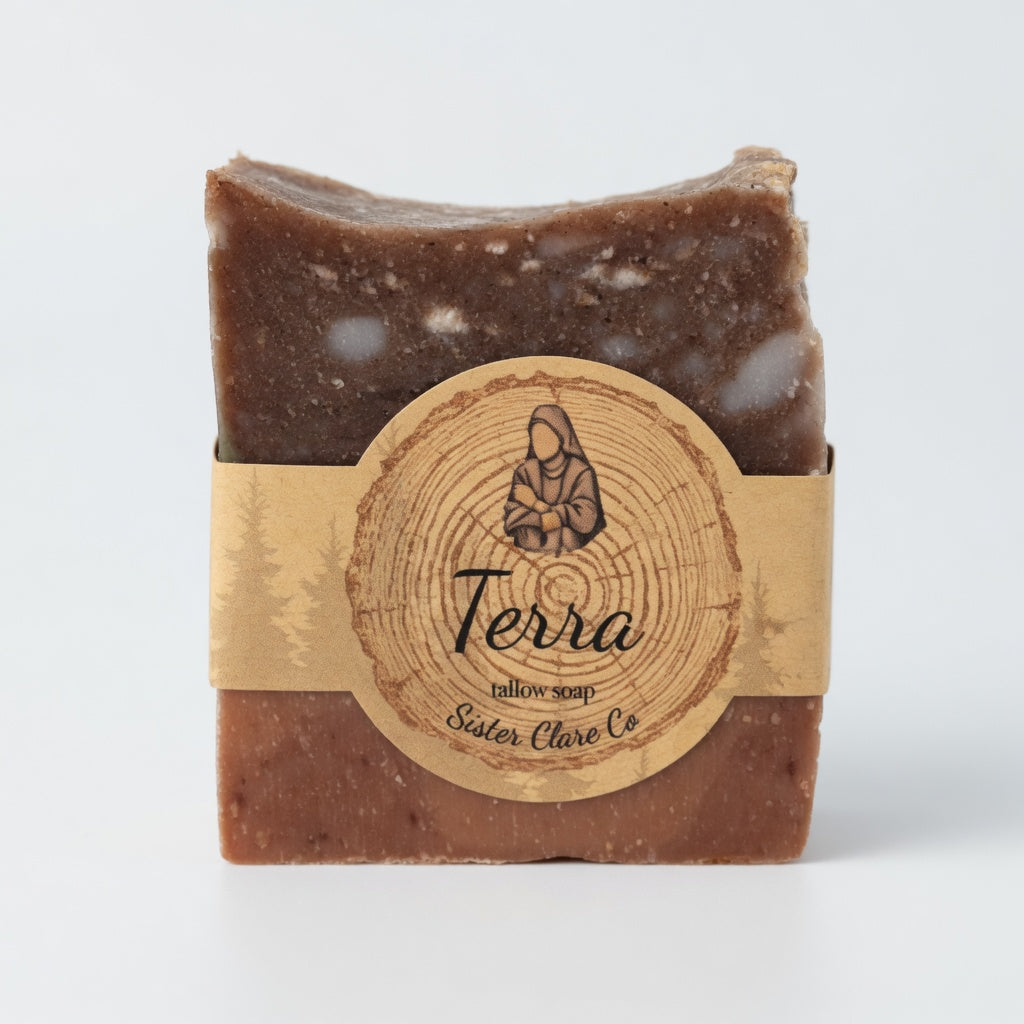Clean neutral product shot of single Terra Tallow Soap bar against a simple soft white background, showcasing exact marbling, texture, and Sister Clare Co. circular nun logo label with strong hero angles.