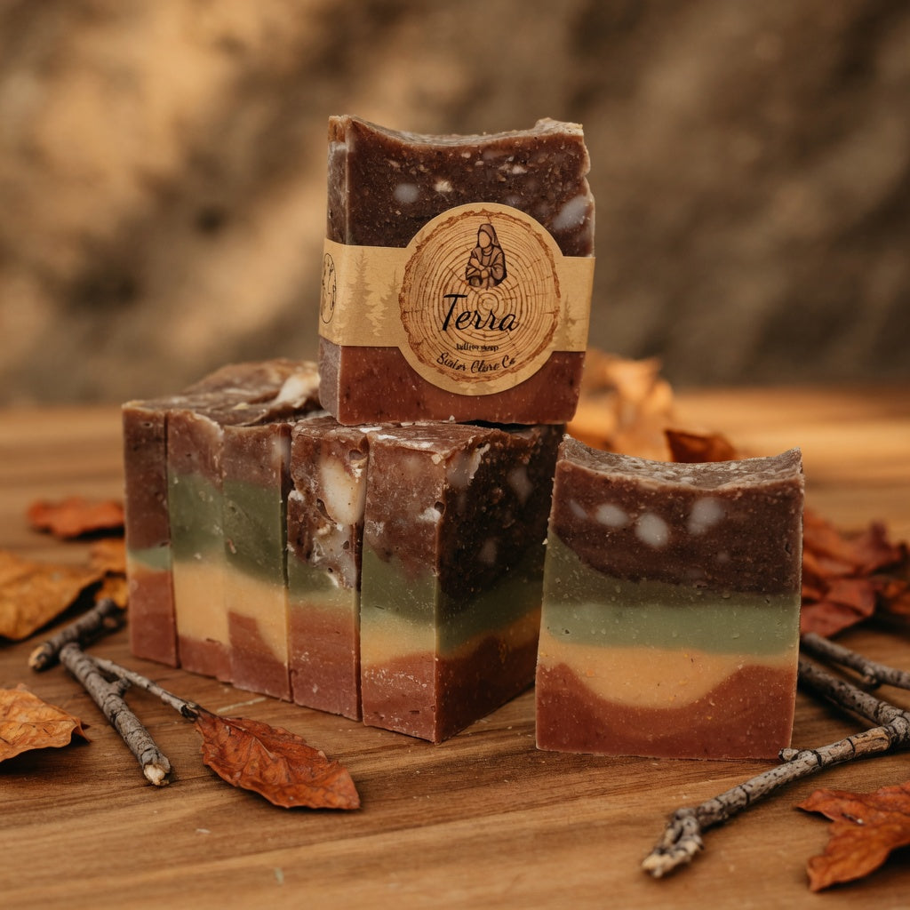 Terra Tallow Soap surrounded by fallen leaves and natural twigs on wood, connecting to the Earth and nature theme while keeping the bar’s exact colors and Sister Clare Co. label visible.